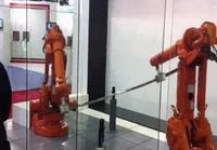 Robotti koskettaa hellästi kärkeään toista kärkeä vastaan ja vasemmalla mustiin pukeutunut masturboi