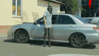Nainen peilailee itseään autosta - nainen peilailee takamustaan auton ikkunasta ja joku yllättää